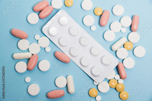 Blister with antibiotics and colorful flatlay pills on blue paper background