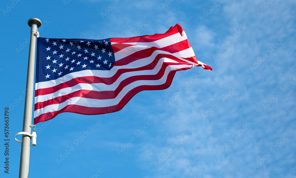 Flag of United States waving in the wind at sunny bright day.