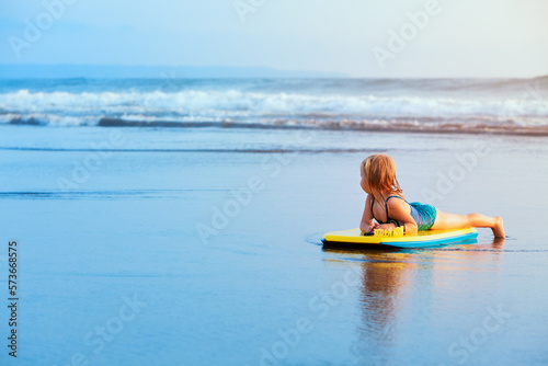 Photography Little baby girl - young surfer with bodyboard has fun on sea beach