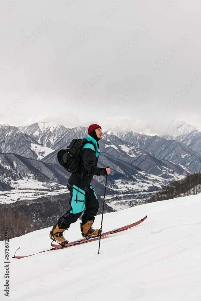 side view of male skier walking against winter mountain landscape