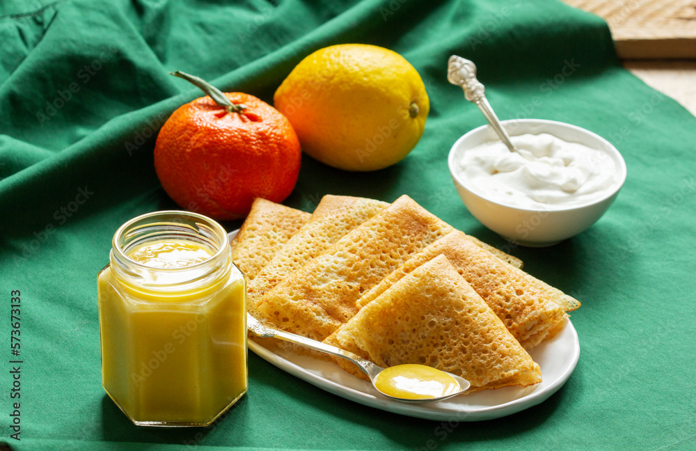 Pancakes served with fruit curd and sour cream, a traditional meal for Maslenitsa and Carnival.