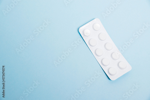 Obraz na plátně White blister pack with antibiotic pills on blue paper background, top view