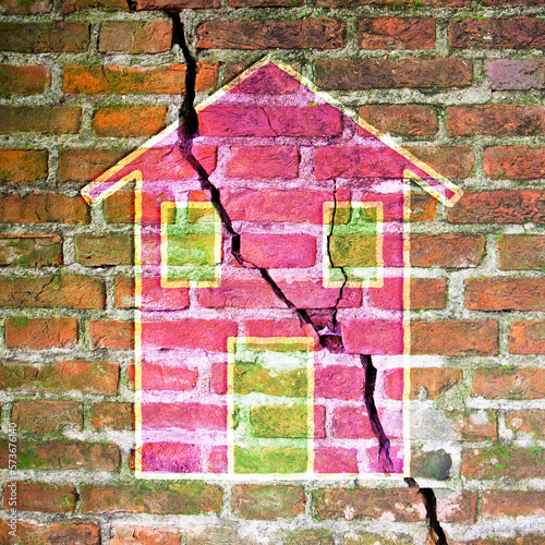 Old deeply cracked brick wall with a colored house drawn on it - earthquake and bradyseism concept photo