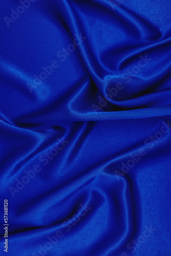 Texture of bright blue silk fabric. Smooth wavy fabric. Can be used as Elegant wallpaper design. Abstract background. Top View, Copy Space