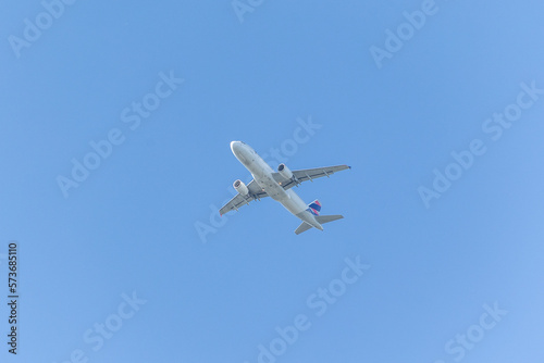 A jet plane flying in a blue sky between clouds. Transportation. Air travel.