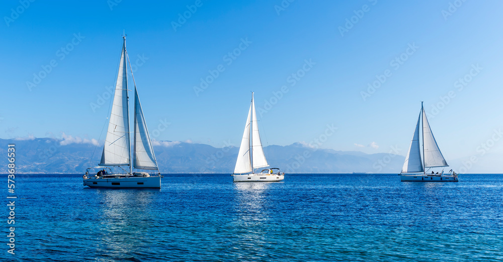 sailing yacht boats with white sails in blue sea , seascape of beautiful ships in sea gulf with mountain coast on background