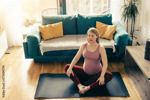 Pregnant Woman Relaxing With Yoga In Living Room