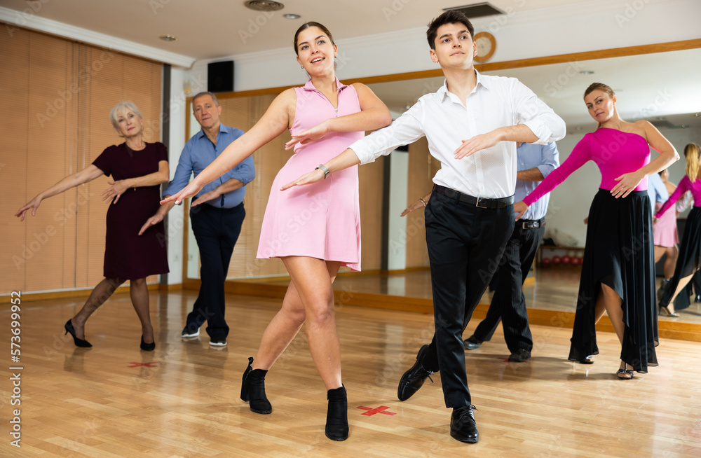 young woman, accompanied by young man, is engaged in modern dance lesson