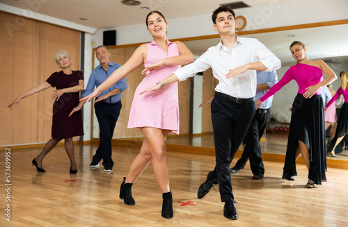 young woman, accompanied by young man, is engaged in modern dance lesson