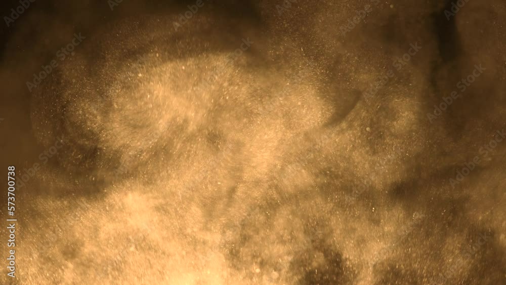 A cloud of yellow sand particles rise up in slow motion