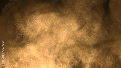 A cloud of yellow sand particles rise up in slow motion