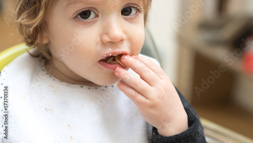 Two years old baby eating pasta with tomato sauce