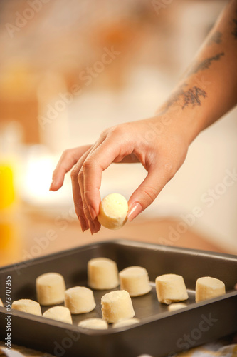 Young woman putting frozen chesse breads on the serving dish.