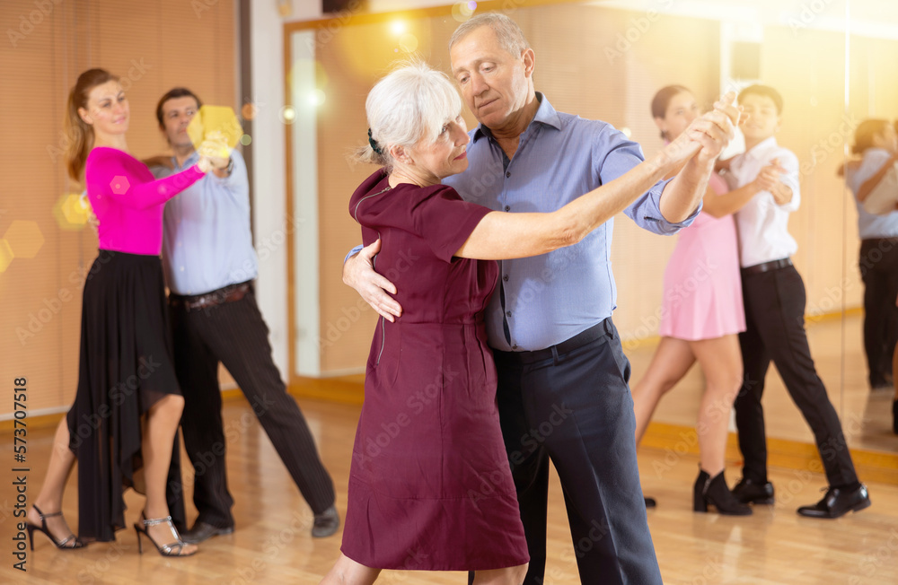 Fototapeta premium Spirited old pair training waltz dance during workout session. Pairs training ballroom dance in hall