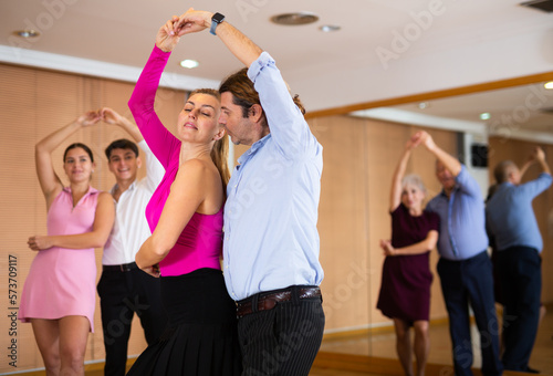 Spirited middle-aged pair training waltz dance during workout session. Pairs training ballroom dance in hall