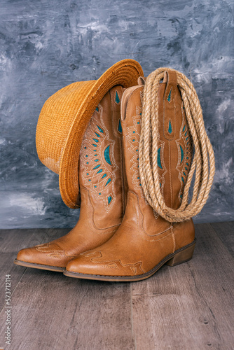Cowboy boots, hat and rope against a gray wall. Adventure and travel concept.