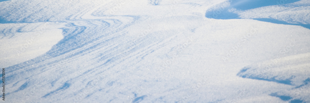 Snow texture. Wind sculpted patterns on snow surface. Wind in the tundra and in the mountains on the surface of the snow sculpts patterns and ridges. Arctic, Polar region. Winter panoramic background.