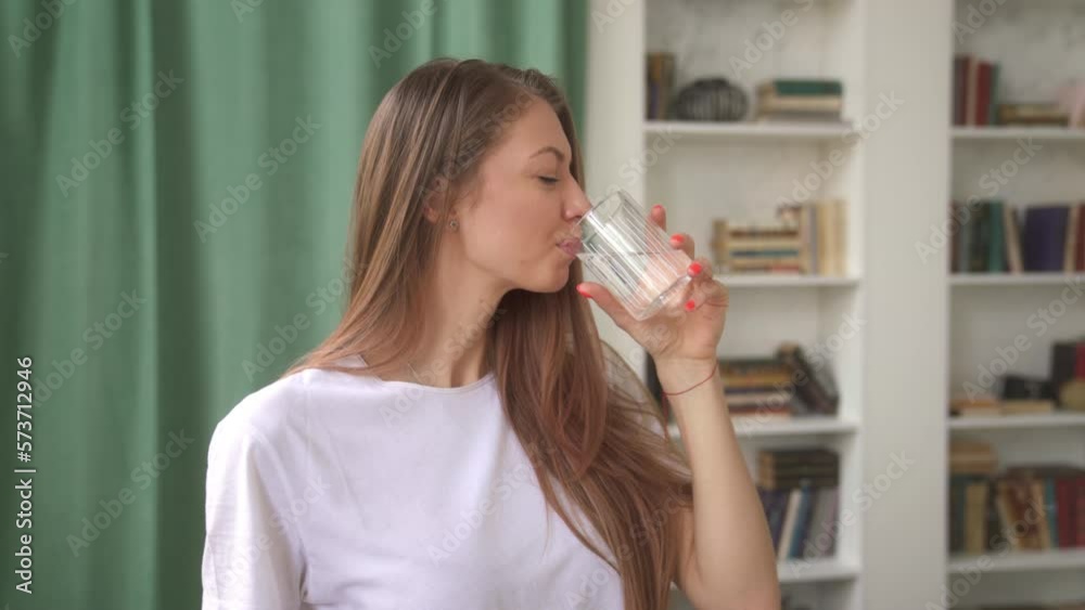 Close up relaxed young woman drinking water looking at camera and smiling. Beauty portrait of young woman with perfect smooth healthy skin drink water from a glass. 4k Close up relaxed young woman drinking water looking at camera and smiling. Beauty portrait of young woman with perfect smooth healthy skin drink water from a glass. 4k