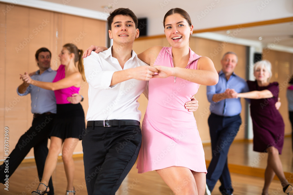 Fototapeta premium Active young pair practicing Latino dance in training hall during dancing-classes. Pairs training ballroom dance