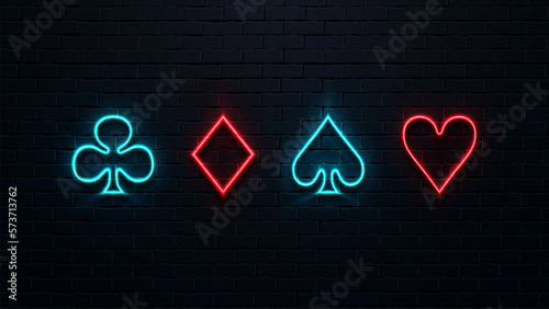 Four neon suits of cards on a brick wall background. Red and blue bright icons: diamonds, hearts, spades and crosses