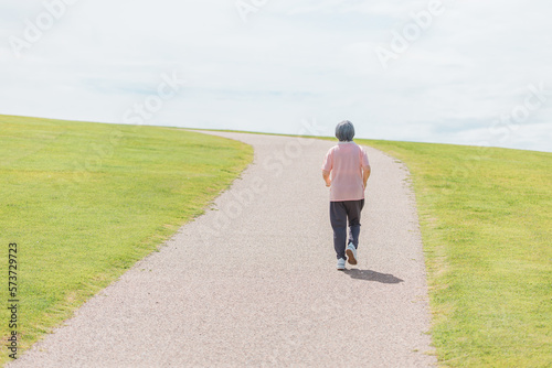 公園でウォーキング・有酸素運動・ランニングする高齢者女性 