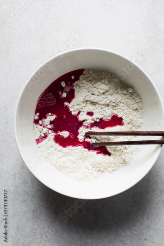Beet juice and flour in a bowl for making pink noodles, process of making pink noodles