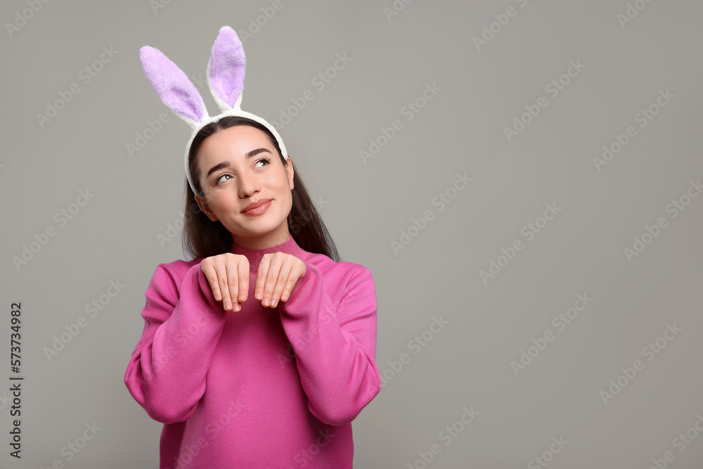 Happy woman wearing bunny ears headband on grey background, space for text. Easter celebration Happy woman wearing bunny ears headband on grey background, space for text. Easter celebration