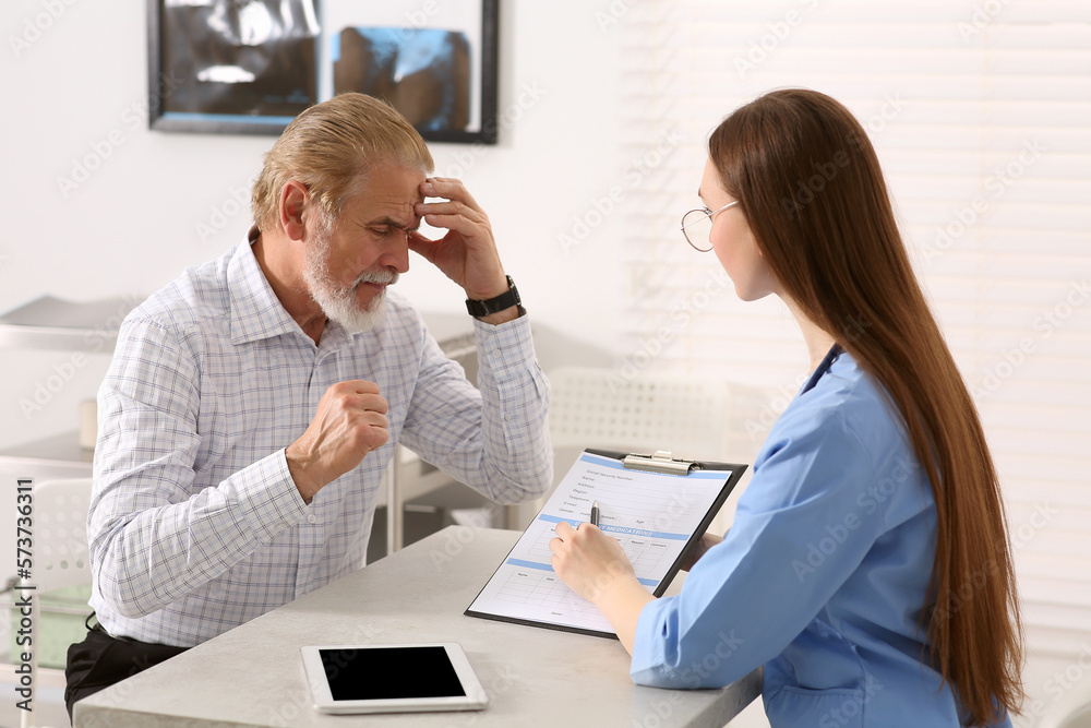 Obraz premium Doctor showing medical card to patient at table in clinic