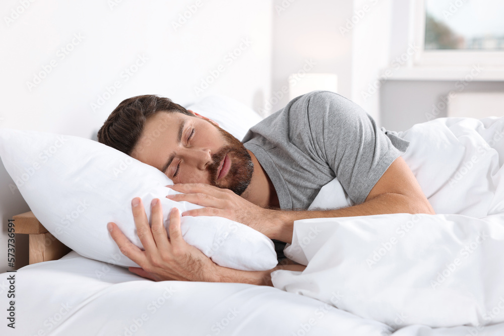 Man sleeping on comfortable pillows in bed at home Man sleeping on comfortable pillows in bed at home