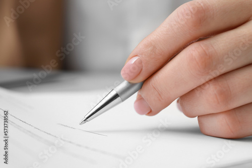 Closeup view of woman signing document at table