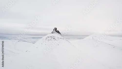 Arial shot orbiting around the top of Trollsteinen, Svalbard. Snowcovered landscape. photo