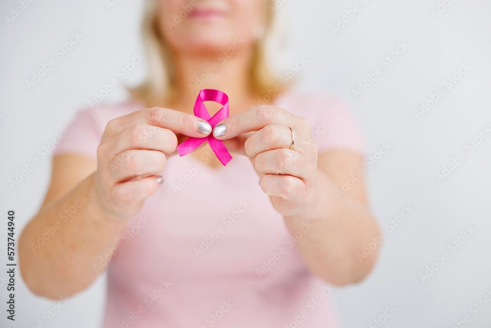 Woman in pink sweater with pink ribbon supporting breast cancer awareness campaign Woman in pink sweater with pink ribbon supporting breast cancer awareness campaign