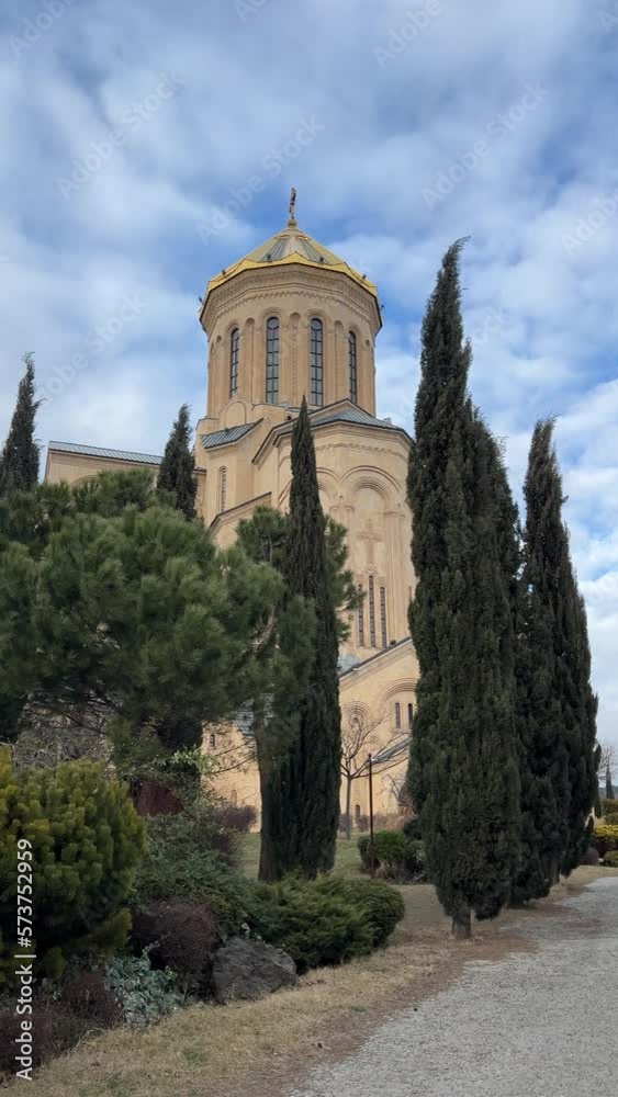 Vertical 4K video. View of Georgian Tbilisi Cathedral of Holy Trinity. Main Orthodox Christian Church of Georgia. Green cypress trees sway in wind. Concept of religion, faith in god, worship. Sameba Vertical 4K video. View of Georgian Tbilisi Cathedral of Holy Trinity. Main Orthodox Christian Church of Georgia. Green cypress trees sway in wind. Concept of religion, faith in god, worship. Sameba