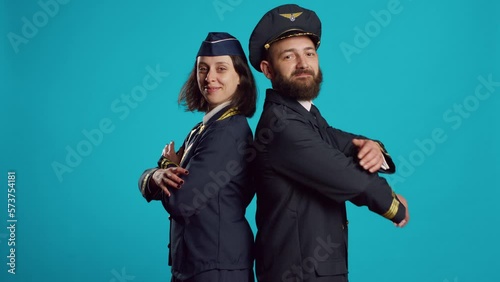 Aircrew members posing with confidence on camera, wearing flying uniforms and smiling. Young stewardess and airplane captain feeling happy about commercial flights occupation. photo