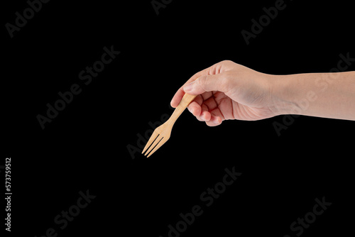 Hand and wood fork on black background.