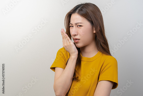 Portrait of pretty brunette hair, disgust smell bad strong asian young woman, girl checking her breath oral with hand expression face disgusting, dislike mouth odor. Isolated on white background.