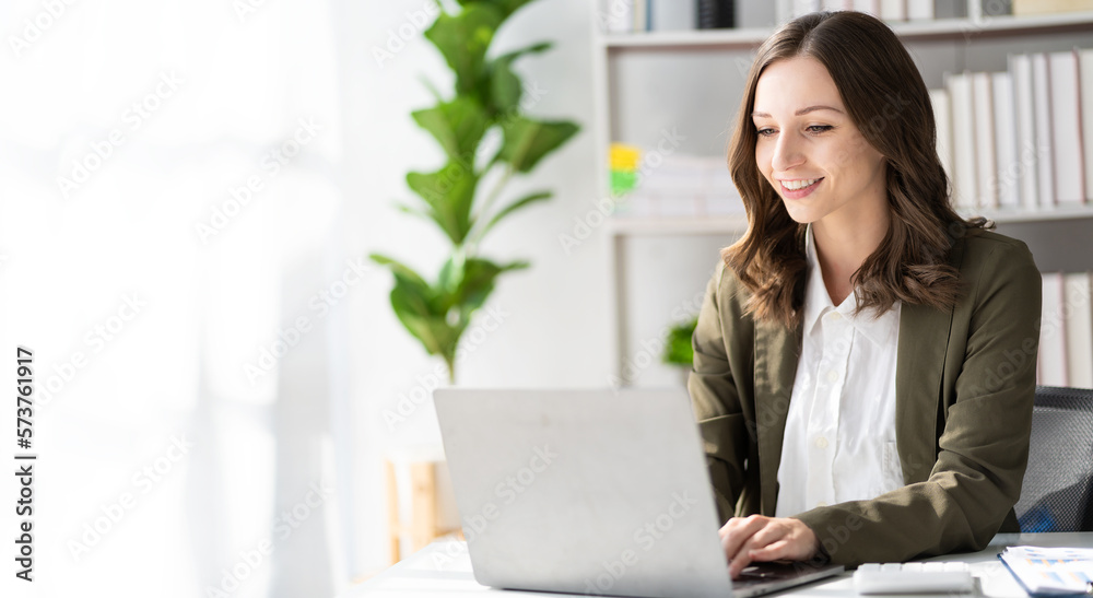 
American businesswoman smiling confidently using laptop computer working on financial statistics presentation with graph document Female accountant analyzing data in office looking at camera - obrazy, fototapety, plakaty 