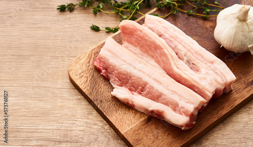 fresh raw streaky pork on wood board with ingredients and thyme leaves on wooden table background. raw streaky pork                       