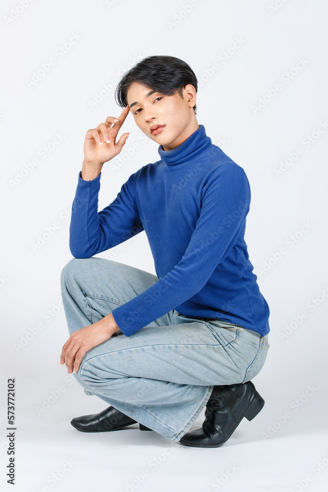 Portrait isolated cutout studio full body shot Asian young sexy slim fashionable LGBTQ gay male fashion model in turtleneck long sleeve shirt jeans leather boots sitting posing on white background Portrait isolated cutout studio full body shot Asian young sexy slim fashionable LGBTQ gay male fashion model in turtleneck long sleeve shirt jeans leather boots sitting posing on white background