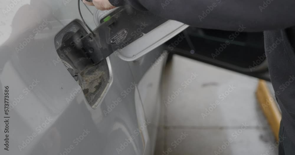 Gas station white caucasian man with wedding ring filling up silver car with opened fuel tank cover and twisting off and storing gas cap then turning to pump. Gas station white caucasian man with wedding ring filling up silver car with opened fuel tank cover and twisting off and storing gas cap then turning to pump.