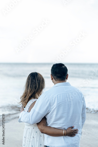 Couple of man and woman embracing while watching the sunset at the beach