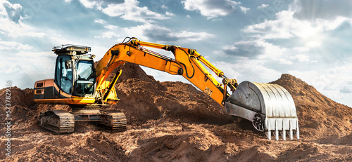 A large yellow crawler excavator moving stone or soil in a quarry. Heavy construction hydraulic equipment. excavation. Rental of construction equipment.