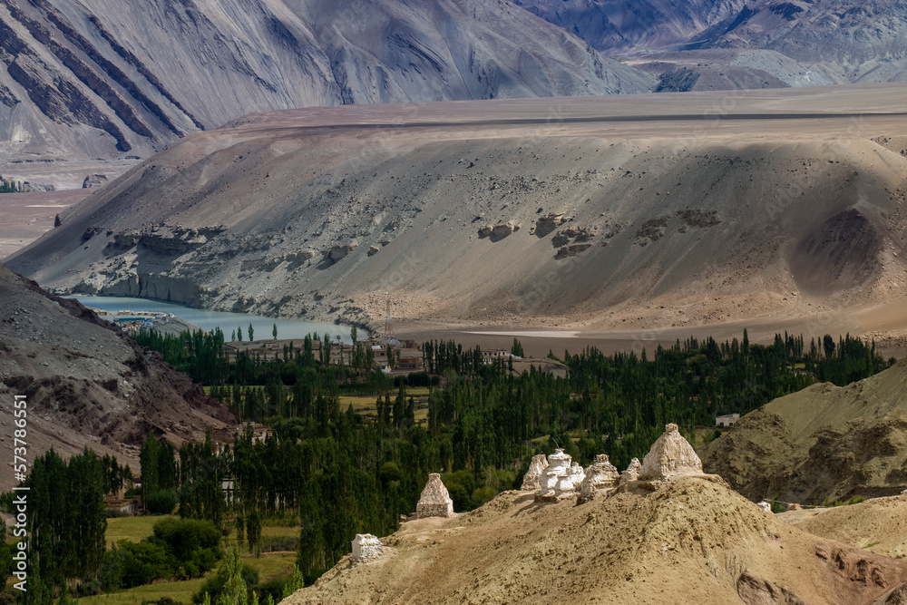 Buddhist Stupa, mound-like or hemispherical structure containing relics , used as a place of meditation. Green trees and Himalayan mountains in the background. Leh, Uninion territory of Ladkah, India.