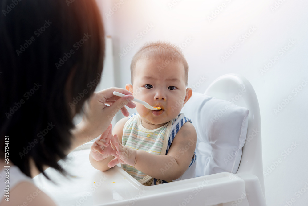 Asia baby boy child sitting eating food on chair at home Asia baby boy child sitting eating food on chair at home