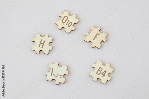 Set of puzzles with 5 biologically important elements with inscriptions on a beige background. Q10, F, H, Inositol, B4