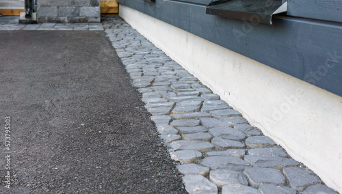 Close-up of a pavement around the house. The courtyard is covered with asphalt and paving stones.