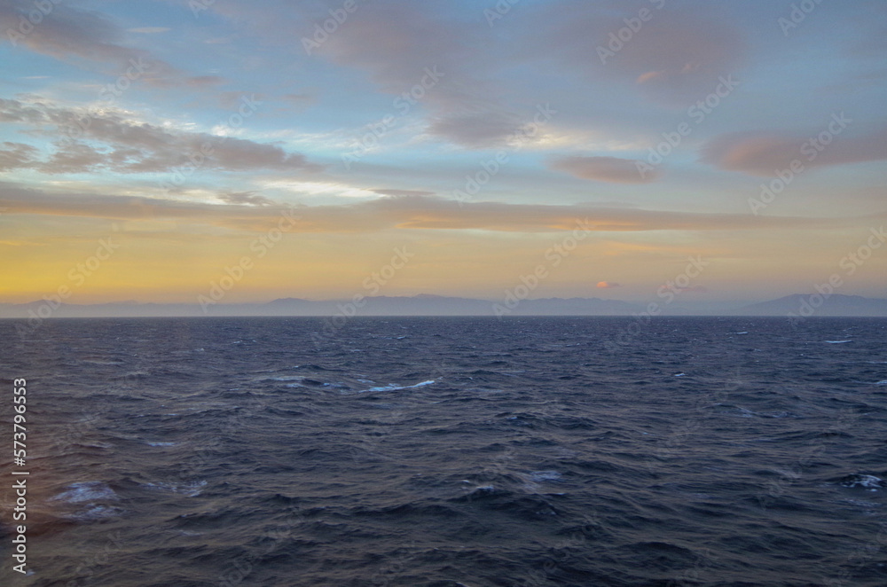 Massive freak wave spray from bow of cruiseship cruise ship liner at sea during Transatlantic Ocean crossing passage on sunny sunset sunrise twilight blue hour day