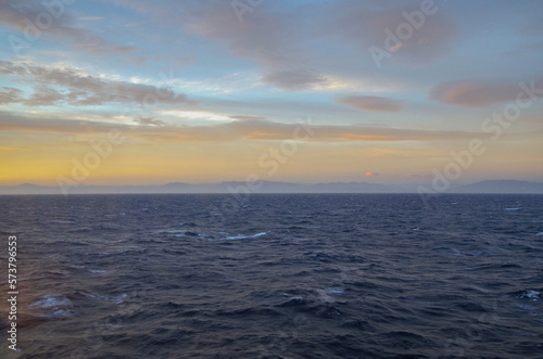 Massive freak wave spray from bow of cruiseship cruise ship liner at sea during Transatlantic Ocean crossing passage on sunny sunset sunrise twilight blue hour day
