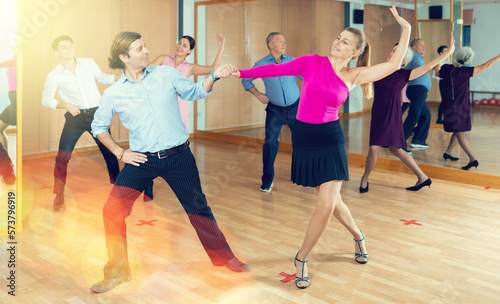 Pair of cheerful adult amateur dancers practicing vigorous playful swing in dance class. Social dancing concept