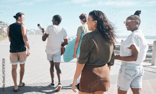 Diversity, walk and friends on beach promenade while on summer vacation or weekend trip together. Friendship, multiracial and group of people people walking, bonding and talking by ocean on holiday.